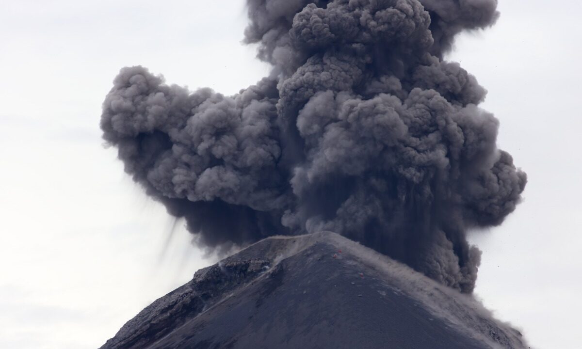 Gęsty, szary słup popiołu wznoszący się nad stożkiem wulkanu Fuego w Gwatemali podczas wybuchowej erupcji