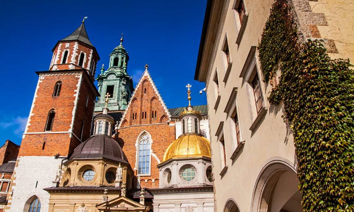 Katedra na Wawelu w Krakowie od strony dziedzińca, ze złotą kopułą Kaplicy Zygmuntowskiej i ceglanymi wieżami na tle błękitnego nieba