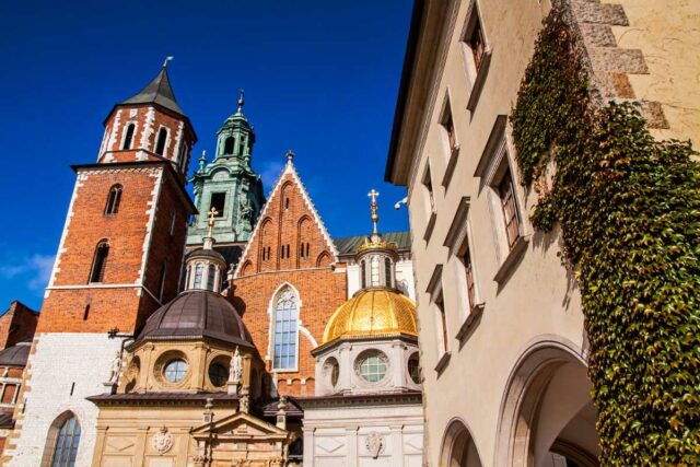 Katedra na Wawelu w Krakowie od strony dziedzińca, ze złotą kopułą Kaplicy Zygmuntowskiej i ceglanymi wieżami na tle błękitnego nieba