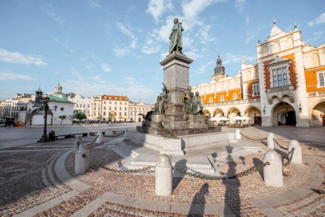 Pomnik Adama Mickiewicza na Rynku Głównym w Krakowie, w tle Sukiennice w porannym świetle