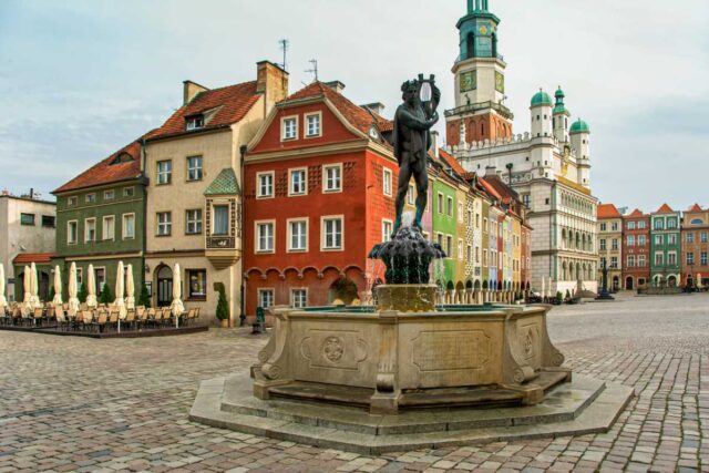 Stary Rynek w Poznaniu: kolorowe kamieniczki, fontanna z posągiem i wieża ratusza